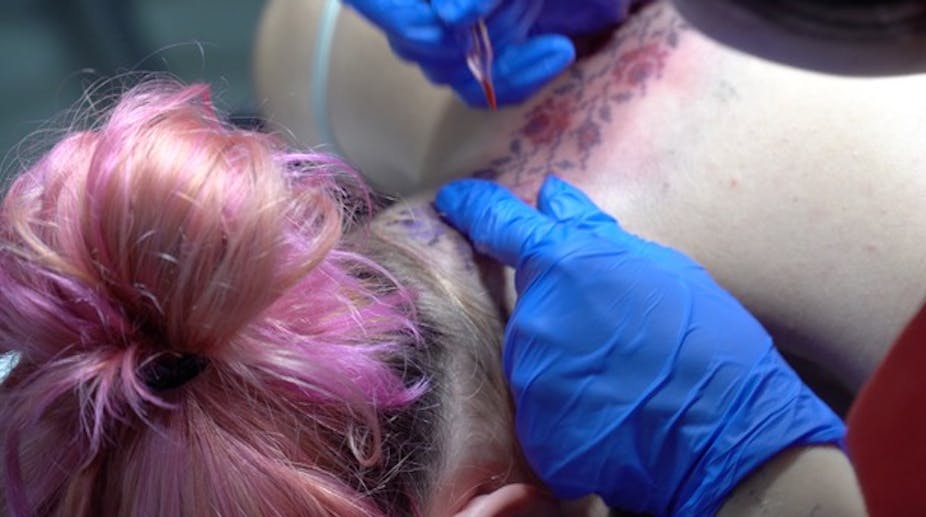 Une femme en train de se faire tatouer sur le cou
