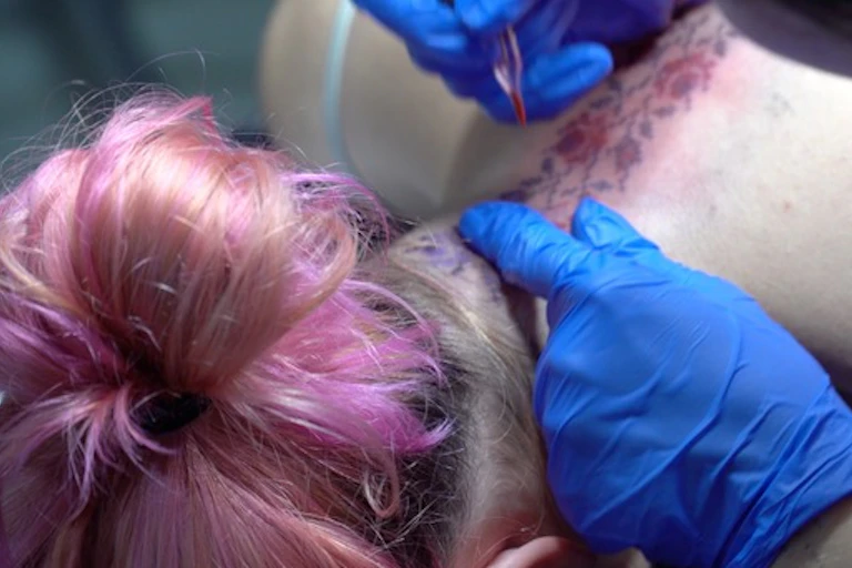 Une femme en train de se faire tatouer sur le cou
