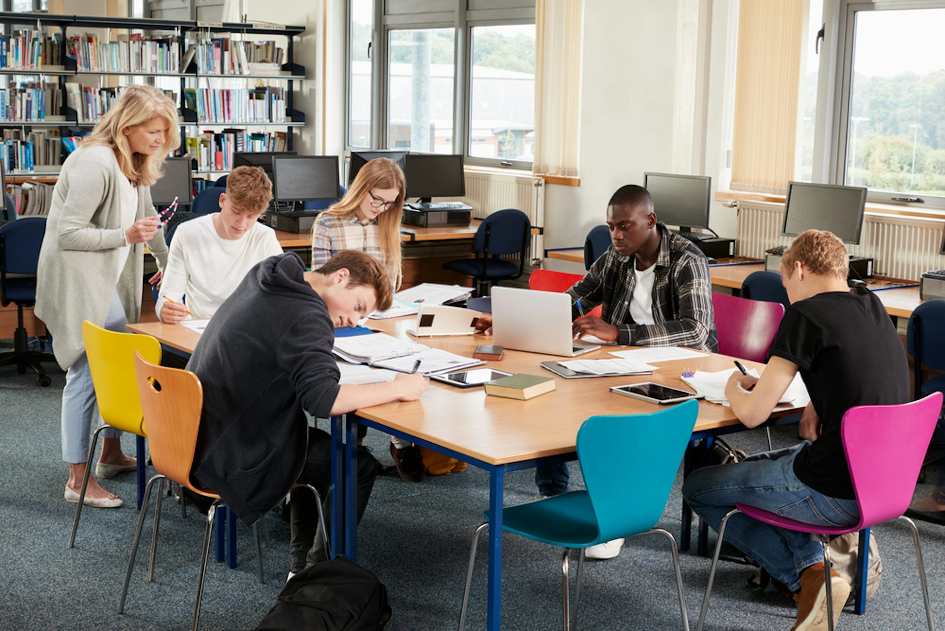 Enseignante travaillant avec un groupe de lycéens en bibliothèque