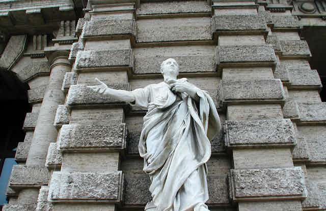 Statue of a classical figure against a wall.