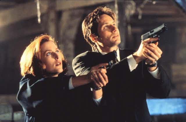 Gillian Anderson and Matt Smith in The X-Files, pointing guns at the sky.