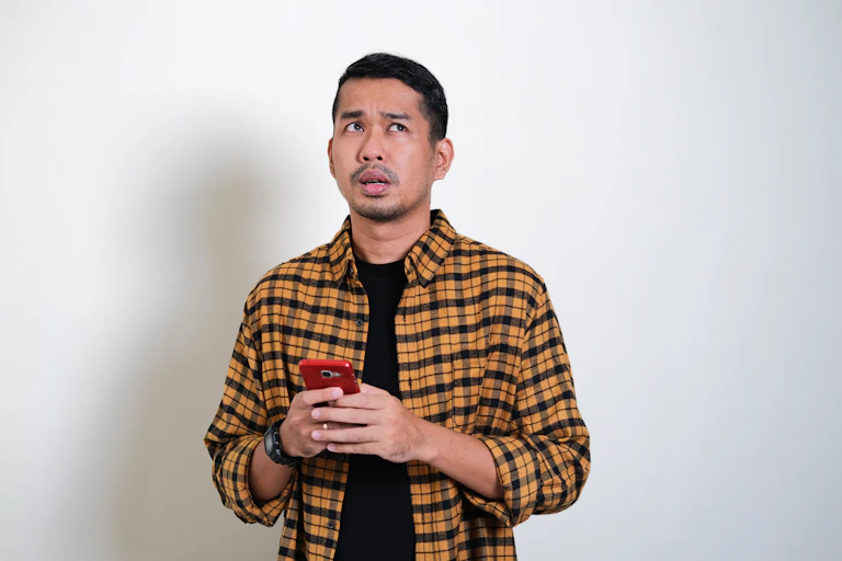 Man holding phone looking confused