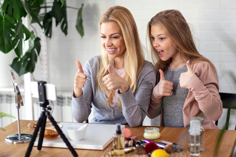 A mother and daughter give thumbs ups to a recording phone.