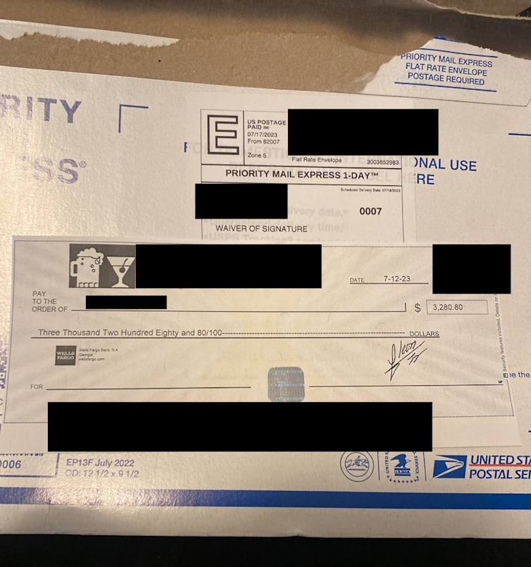 A mailed envelope and a check with names obscured