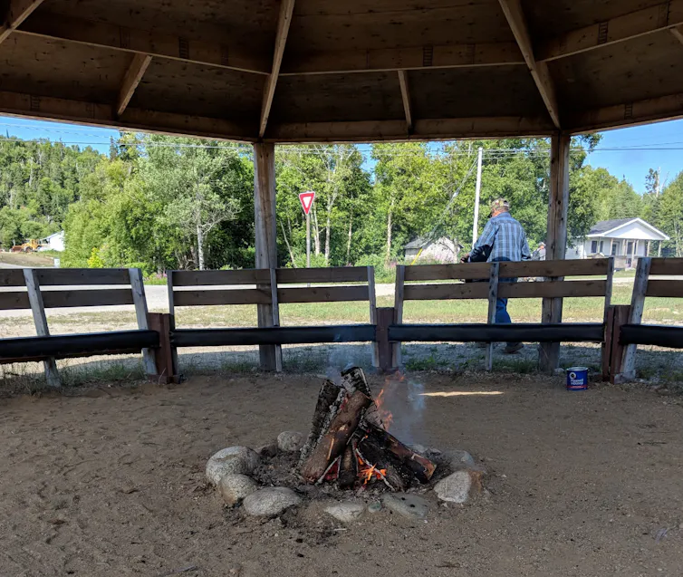 A fire burning in a circle of rocks under an open-air enclosure.