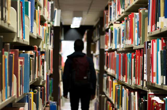 A student walks through library shelves.