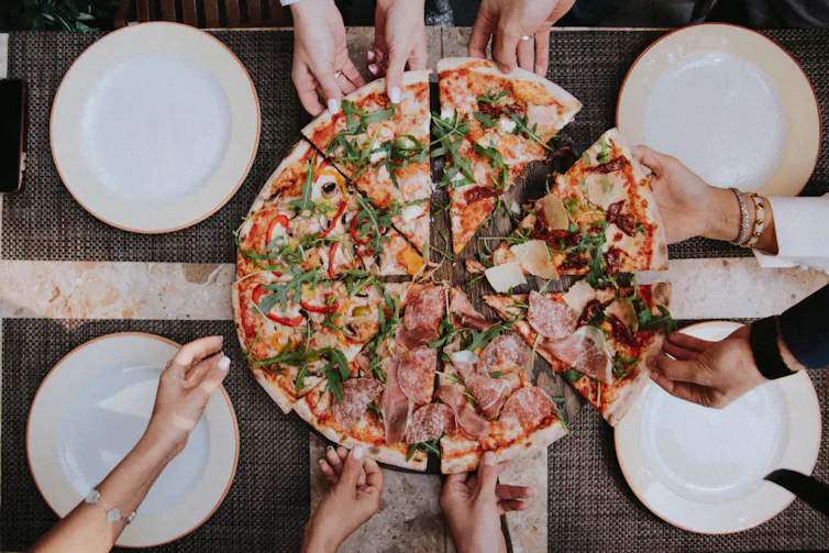 Pizza slices with hands reaching for them