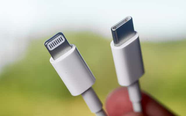 Close-up of two similar looking white charger plugs, one is Apple Lightning and one is USB-C