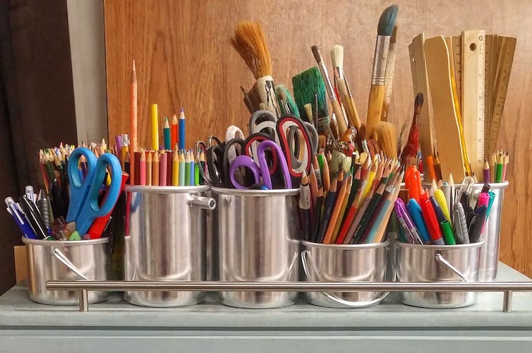 Containers holding pencils, scissors, paint brushes and rulers.
