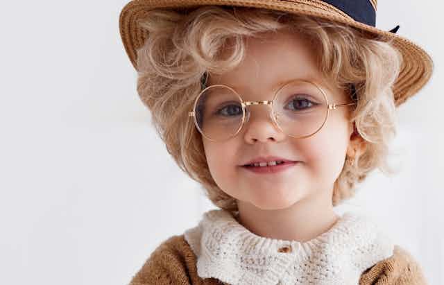 Young girl wearing hat and glasses, dressed up as old woman
