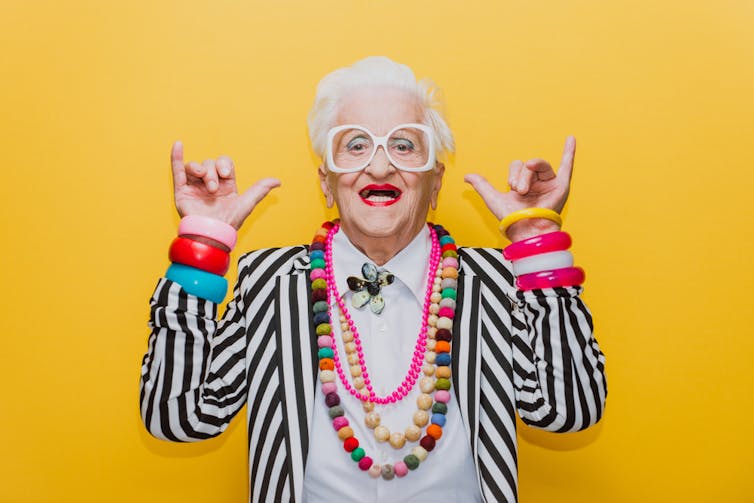 Older woman dressed in modern clothes enjoying herself making hand signals