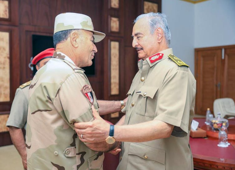 Libyan military commander Khalifa Haftar shakes hands with Egyptian military officer Osama Askar