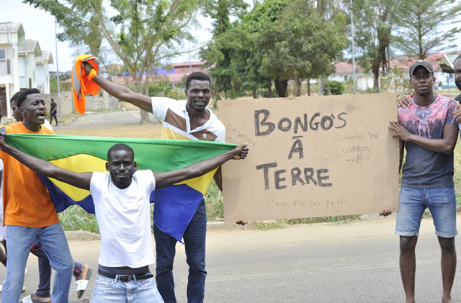Des manifestants brandisent un drapeau gabonais et une pancarte proclamant « Bongos à terre »