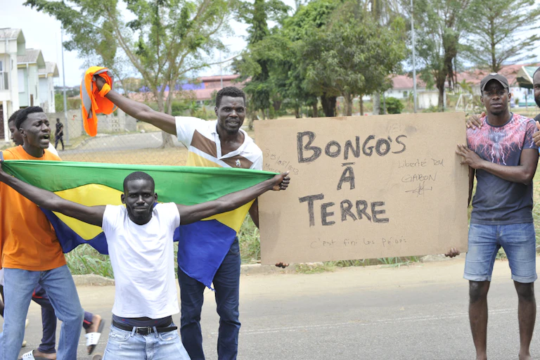 Des manifestants brandisent un drapeau gabonais et une pancarte proclamant « Bongos à terre »