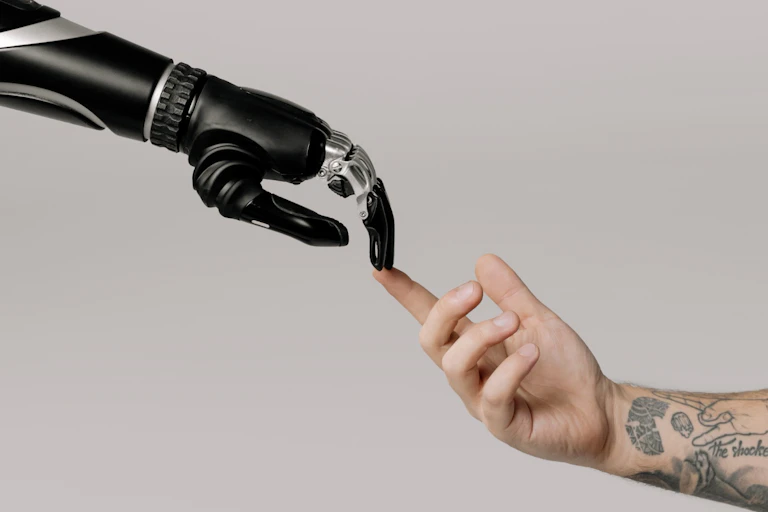 Mão robótica toca com os dedos uma mão humana