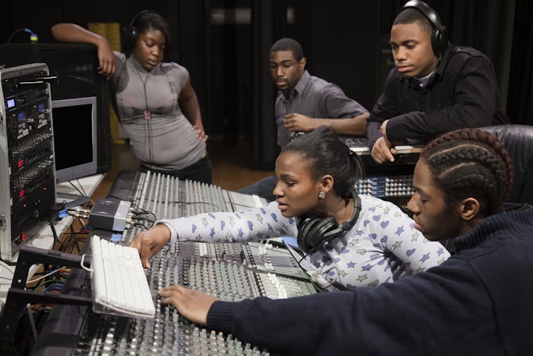 A group of students work with a sound mixer.