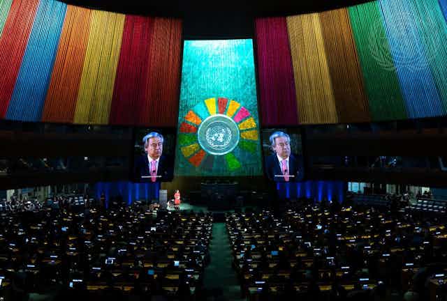A wide view of auditorium at the opening of the Sustainable Developments Goals Action Weekend, with Secretary-General António Guterres on screen surrounded by colourful banners 