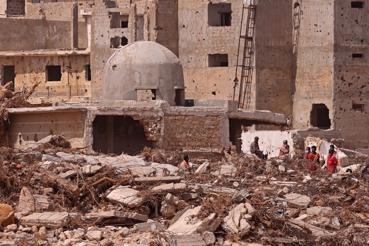 Rescue workers in bright-colored clothing walk amidst rubble in North Africa.