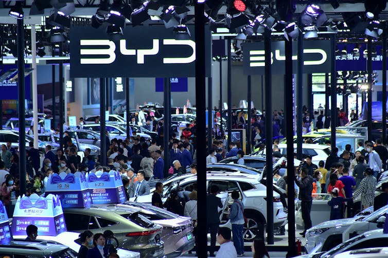 People stand near dozens of electric vehicle models in the BYD booth during the 2023 Shenyang International Auto Show.