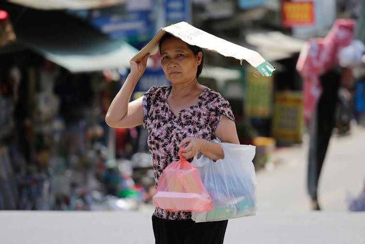 Une femme se protège du soleil extrêmement chaud en marchant dans une rue pendant une vague de chaleur intense à Hanoï
