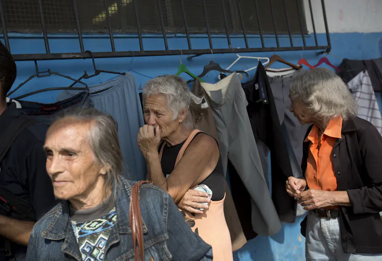 Três idosas aguardam numa fila