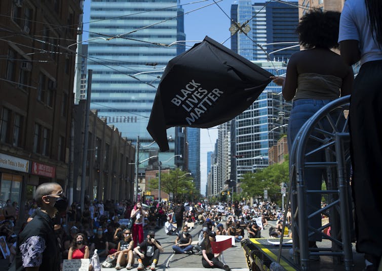 A woman waves a black livea matter flag on a downtown Toronto street