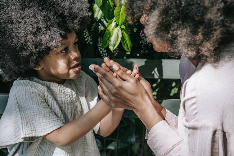 A mother and child play a game with their hands.