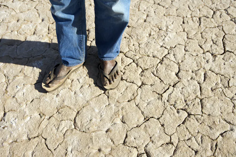 An Aboriginal man stands on parched ground in the Kimberley region of Western Australia.