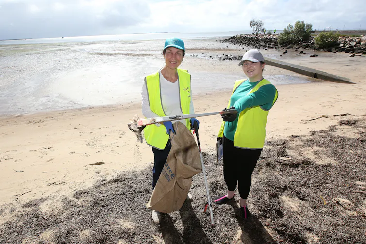 Two volunteers pick up rubbish on a beach