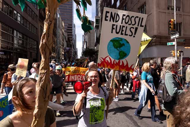 A crowd in New York City holding signs. One reads 'End fossil fuels!'