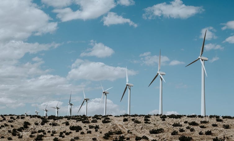 A row of wind turbines on a desert plain.