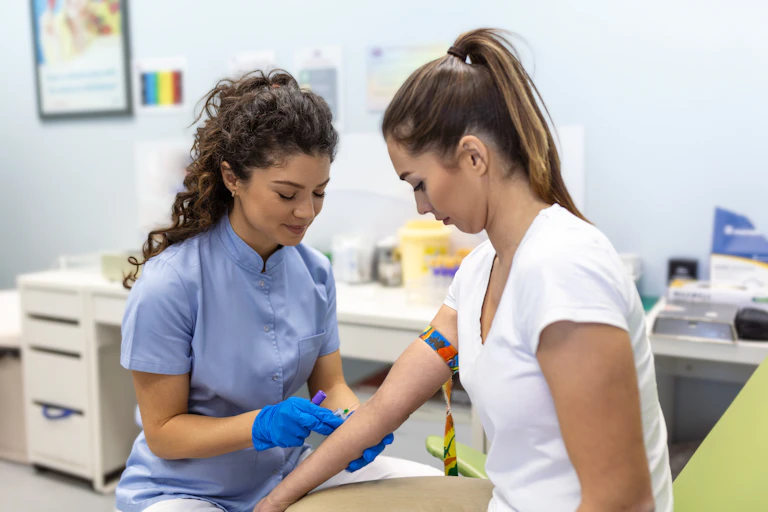 A woman has her blood taken by a female nurse.