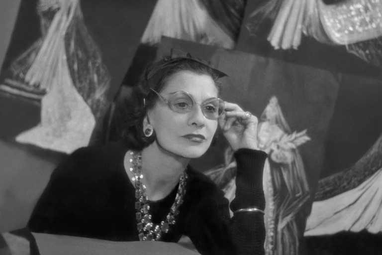 Chanel in glasses with her designs.