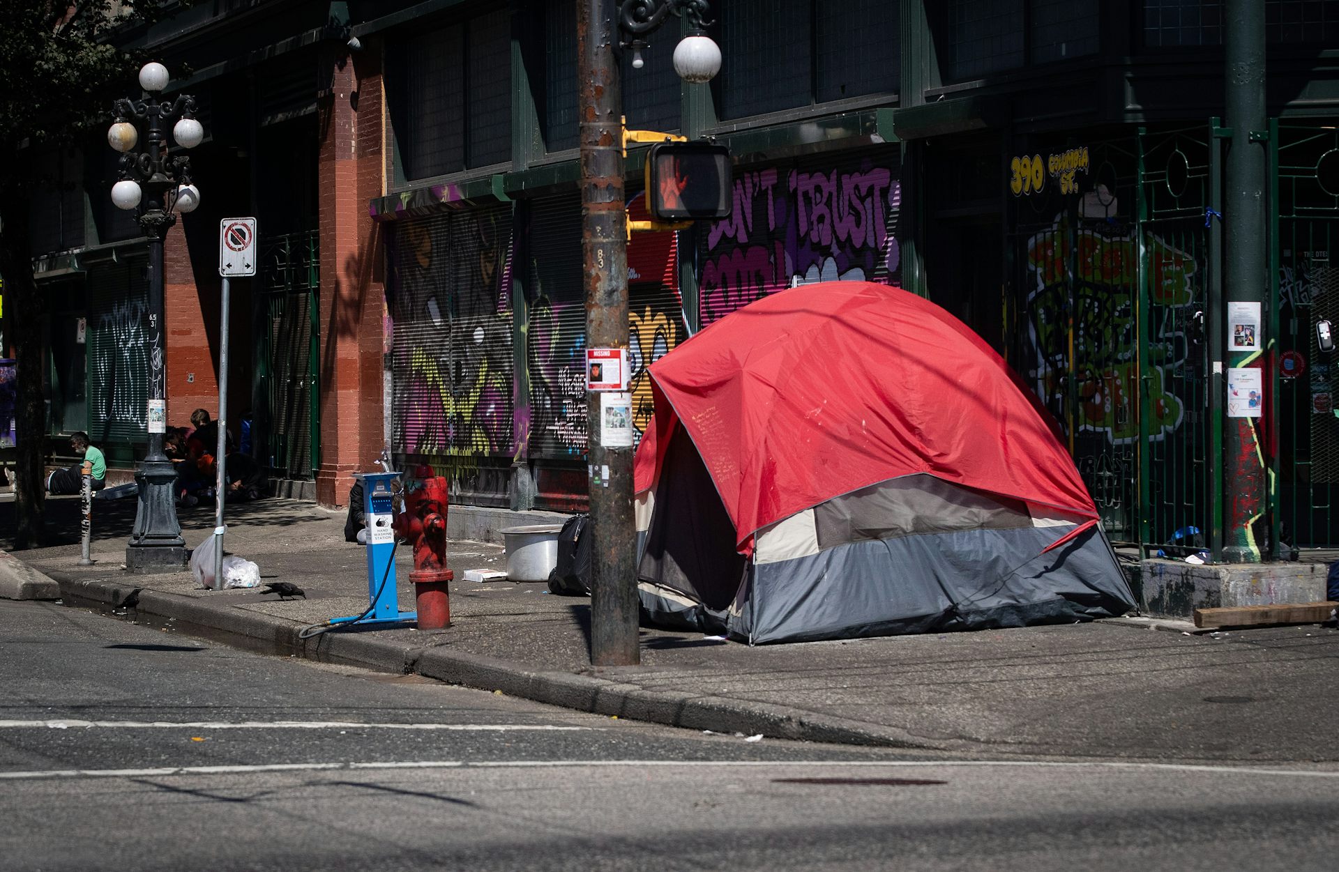 Une tente rouge sur le bord d'une route. Un mur avec des graffitis en arrière-plan 