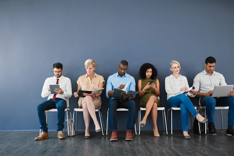 A diverse group of people seated in a line, awaiting something