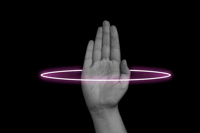 Hand surrounded by a neon pink loop against a black background