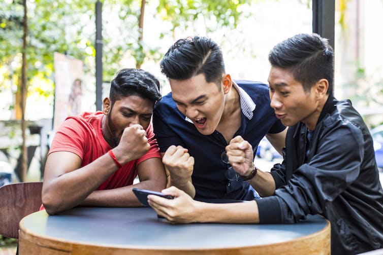 Group of friends watch a game on a phone.