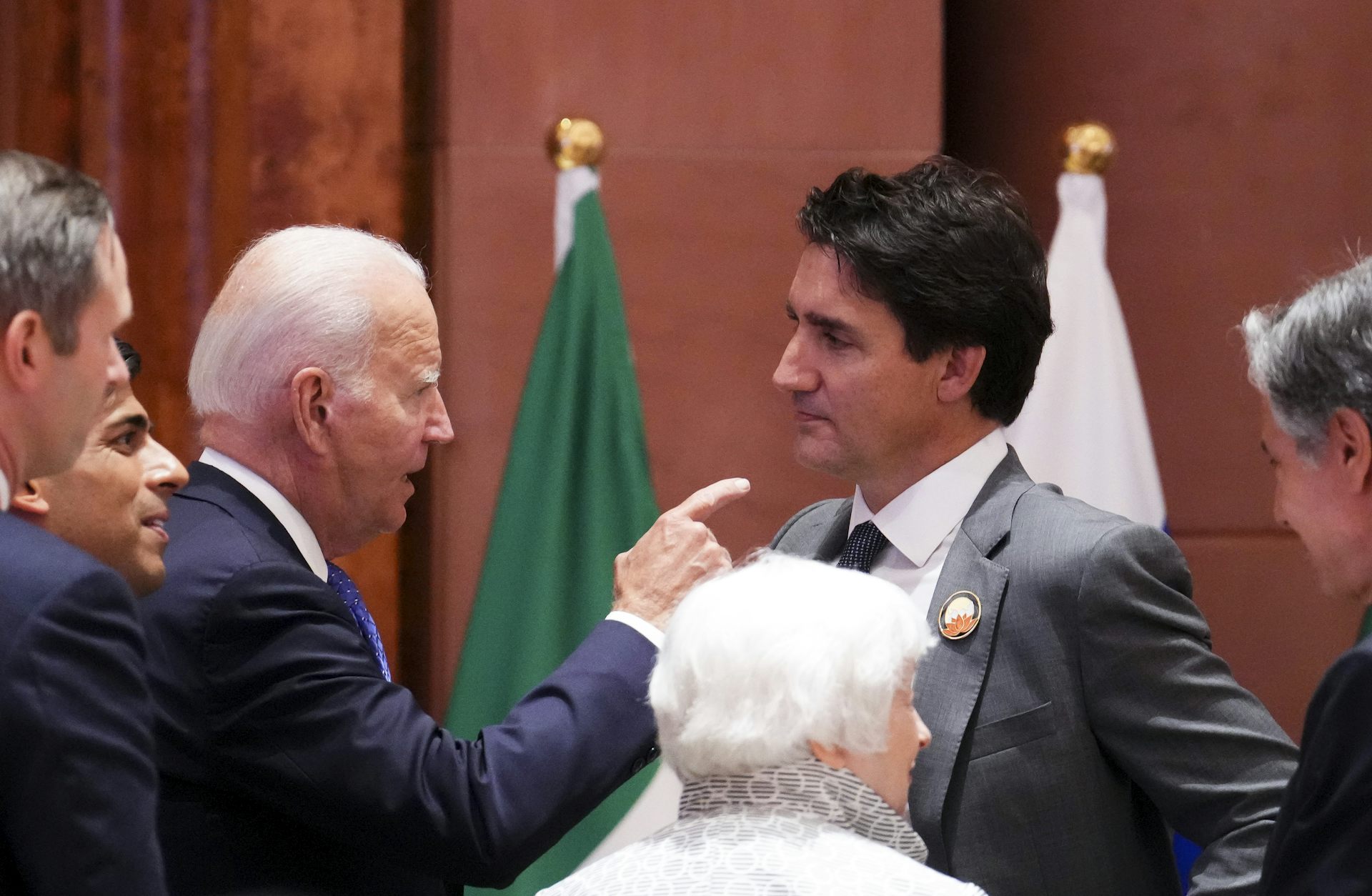 An older man talks to a younger man, pointing at him as he speaks.