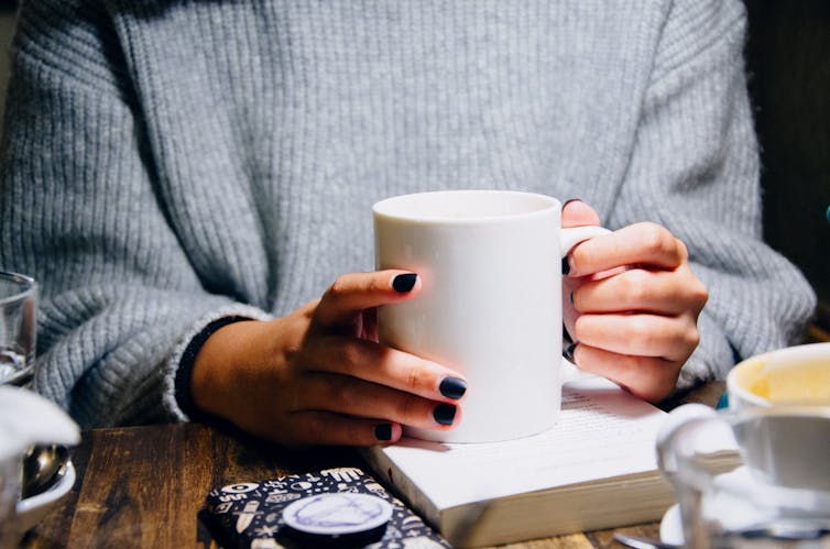 A young woman holds a cup.