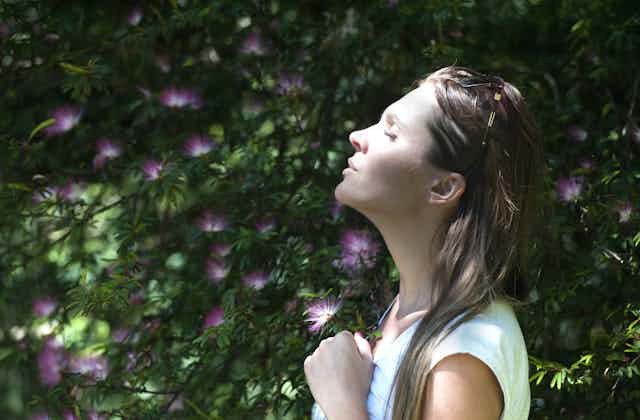 A young woman closes her eyes and tilts her head to the sun.