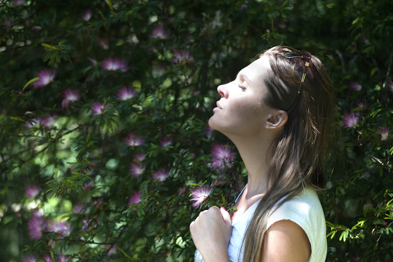 A young woman closes her eyes and tilts her head to the sun.
