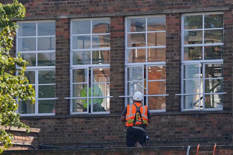 Person in hi-vis looking in through school windowthrough