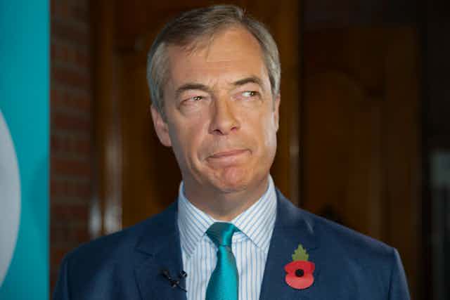 Nigel Farage wearing a suit, blue tie and poppy.