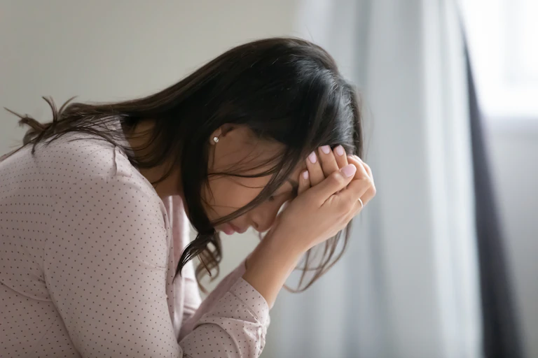 Side view of a young woman with her head resting in her hands