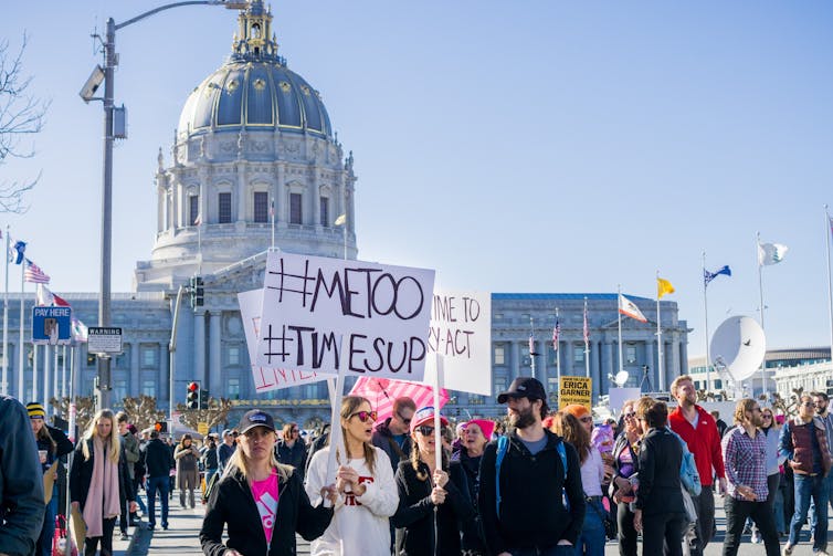 Participants in a MeToo march hold signs in front of the domed San Francisco city hall