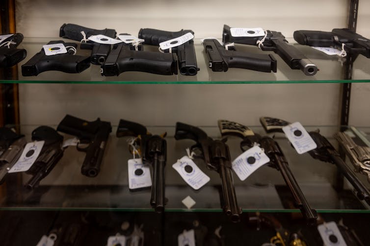 Guns lying on glass display shelves.