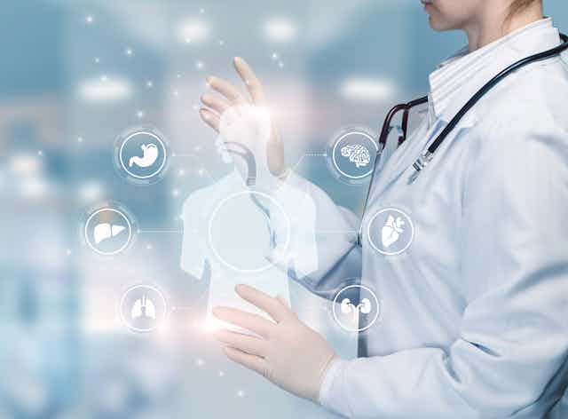 Cropped image of a person in a white coat and stethoscope with an illustration of a human figure and organ systems