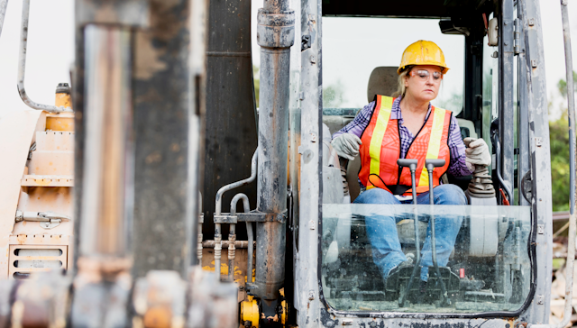 Woman construction worker operating an earth mover.
