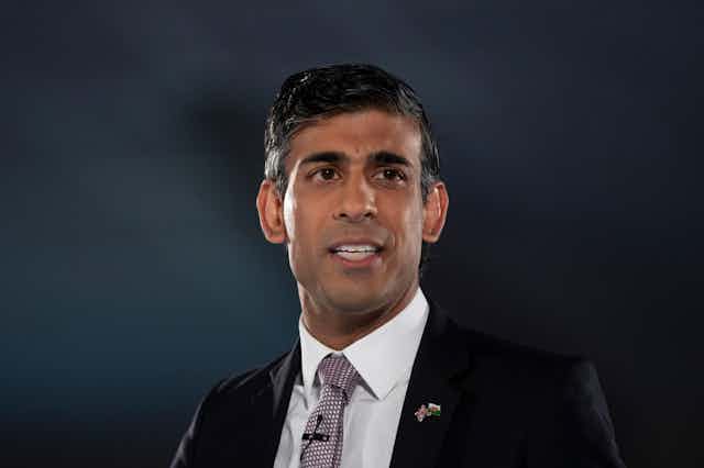 Rishi Sunak in a suit on a dark background.