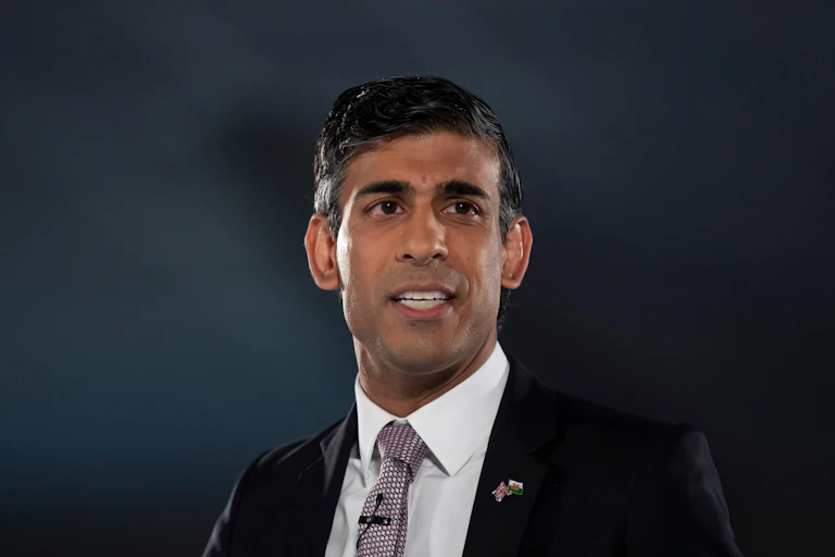 Rishi Sunak in a suit on a dark background.